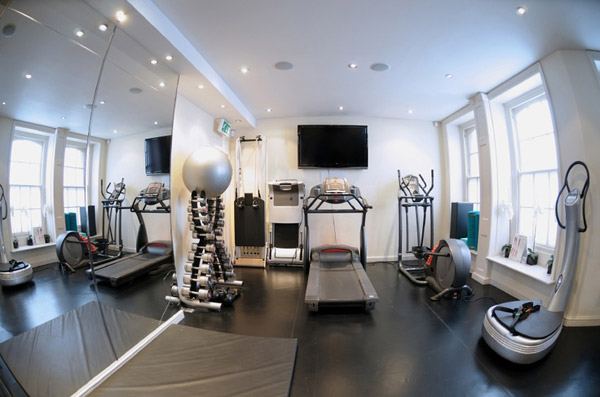 Fish eye lens photo of a home gym with ample cardio equipment, nice dumbbell selection and great lighting