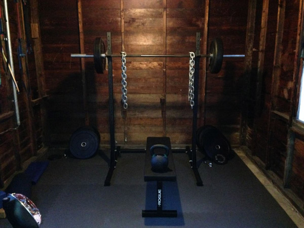 Simple one car garage gym - squat stand, bumpers, bench, kettle. WOD away