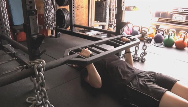 Floor presses with a Swiss bar using chains instead of plates for dynamic lifting