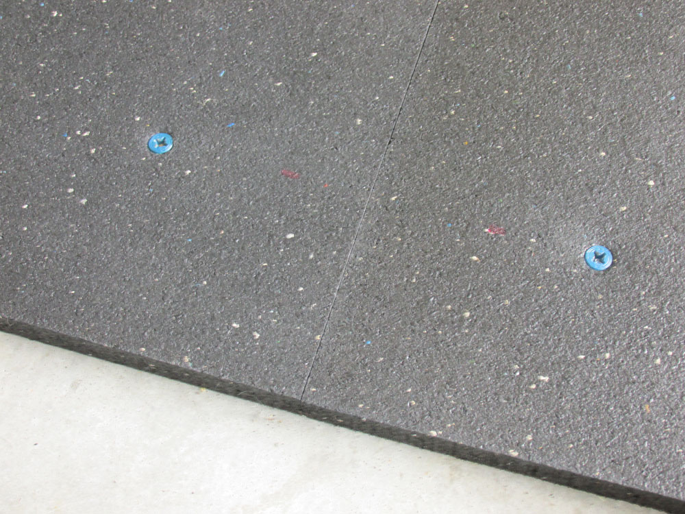 Two stall mats side-by-side and flush being held in place with small anchors