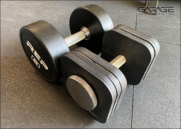 50-lb round, commercial-grade dumbbells next to a 50-lb Ironmaster Quick Lock Dumbbell